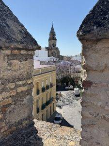 Blick durch Steinmauer auf historischen Kirchturm Blick auf die Iglesia de San Miguel
