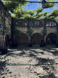 Steinmauer-Innenhof mit Rundbogenfenstern und Grünpflanzen Museumsreife Bodega