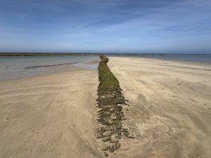 Felsdamm am Sandstrand unter blauem Himmel Uraltes Bauwerk