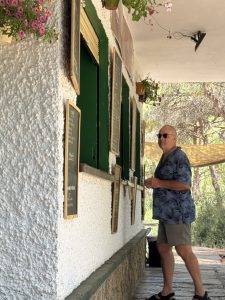 Person neben Gebäude mit Fensterläden und Blumenampeln Pause im Biergarten