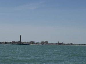 Küstenstadt mit hohem Turm und ruhigem Gewässer Vorbei an Chipiona