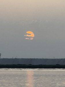 Oranger Mond über stillem Gewässer Diesiger Sonnenaufgang