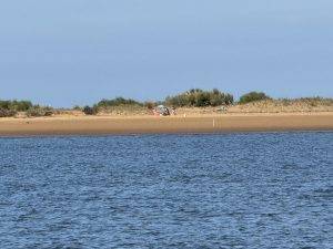 Strandspaziergang mit Sonnenschirm Auf der anderen Uferseite wird geangelt