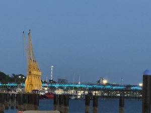Abendlicher Hafenblick mit gelbem Kran und beleuchteter Brücke Die Rio Tinto Brücke wird abends beleuchtet